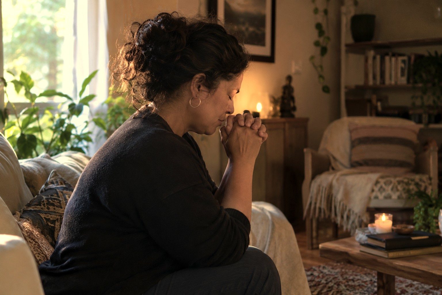 Hands clasped in prayer by candlelight