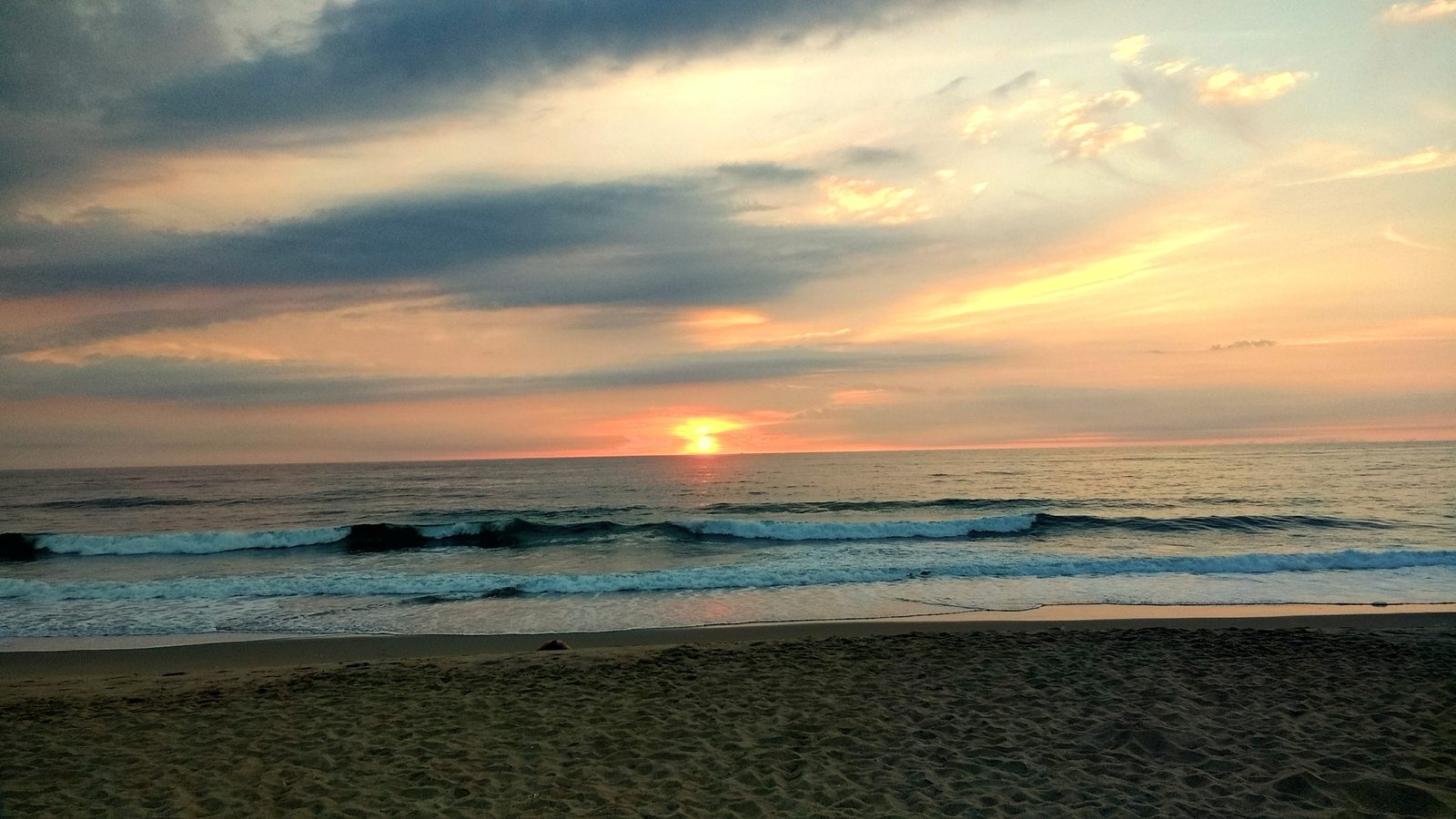 Sunrise over gentle waves under a pink and gold sky