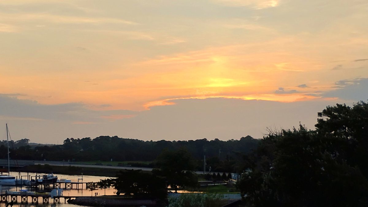 A gold sunset over a quiet harbor with docks and a boat