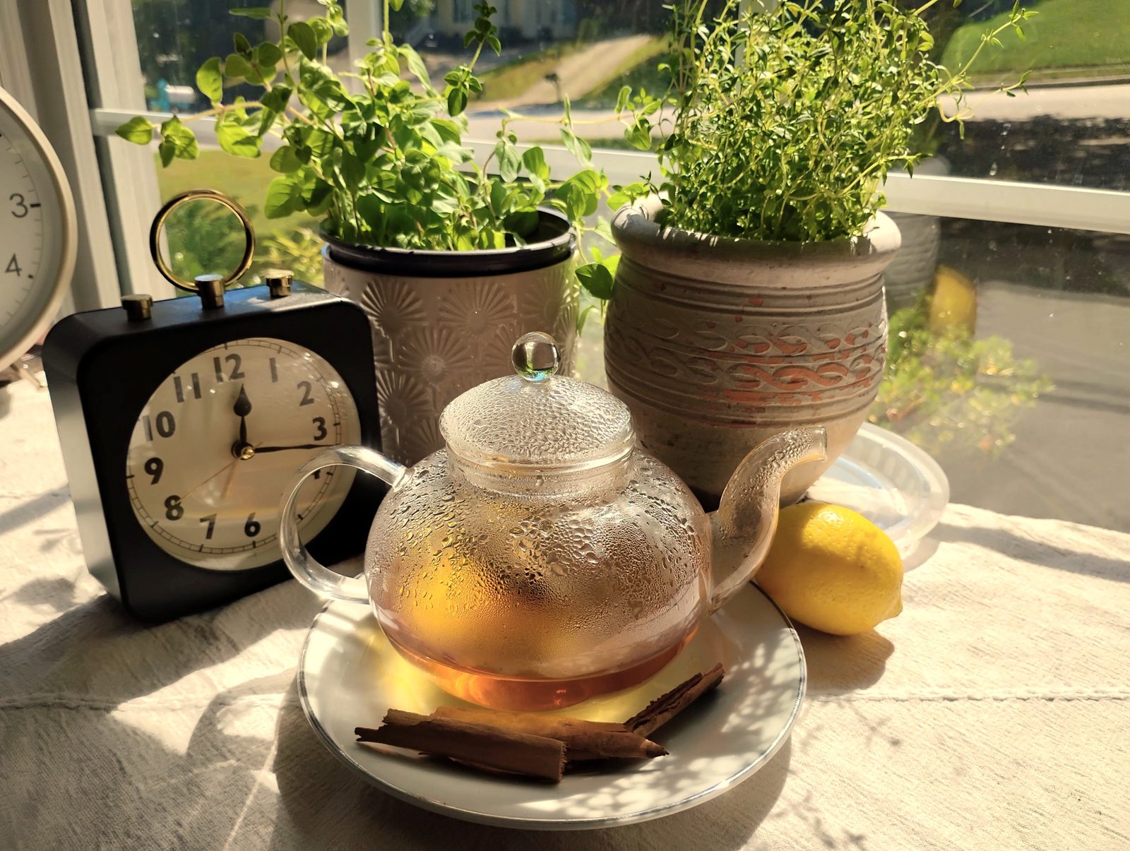 Tea, cinnamon and herbs in a still life beside a clock